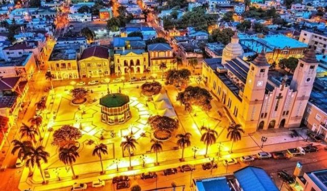 A town square and surrounding buildings illuminated at dusk